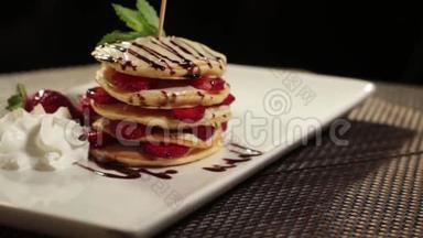 放在桌子上的盘子上装饰着草莓的一部分煎饼的照片，镜头在桌子上旋转